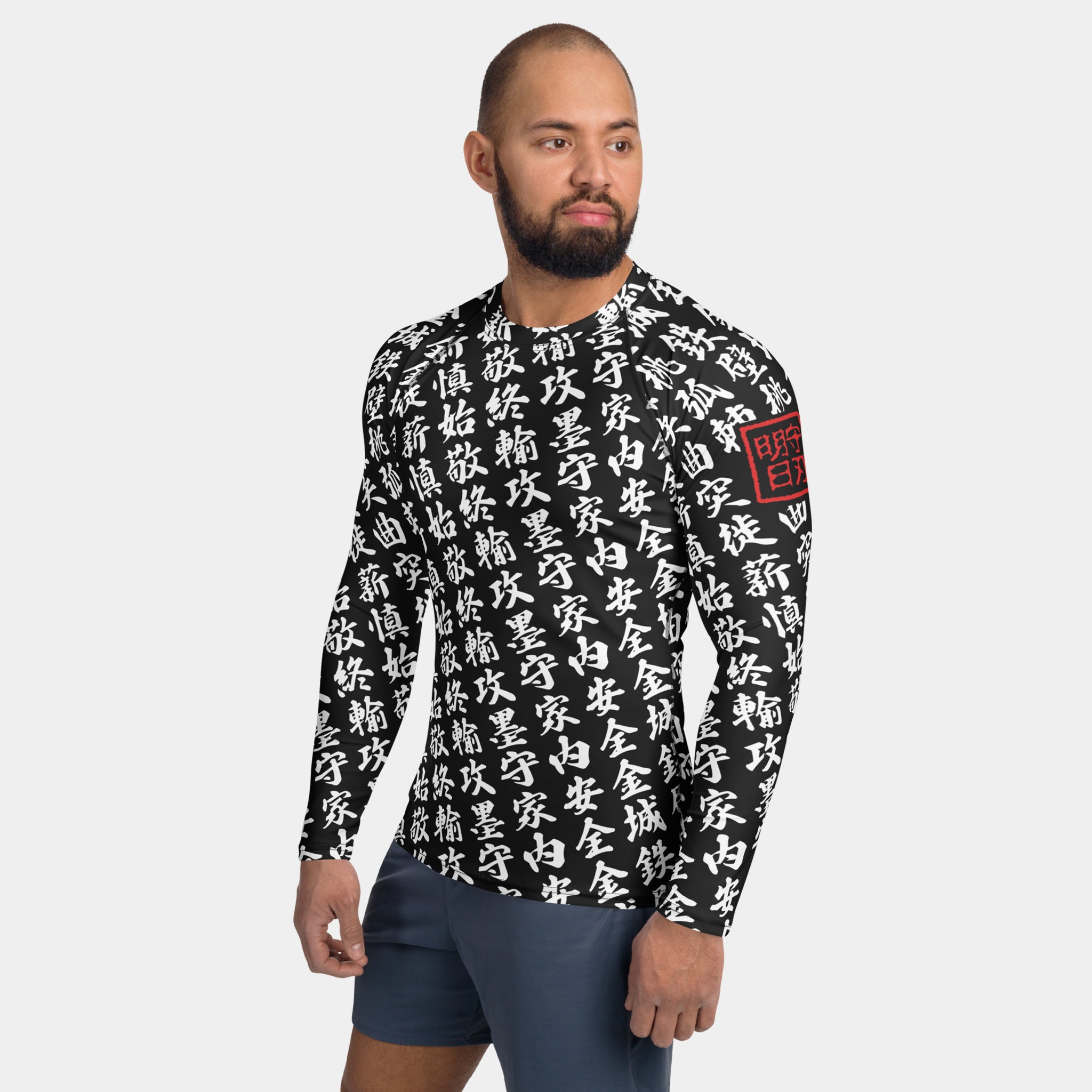 Man wearing the SPARS TOO MUCH KANJI long-sleeve BJJ rash guard in Iron Black and White, with white kanji and a red seal on the left sleeve
