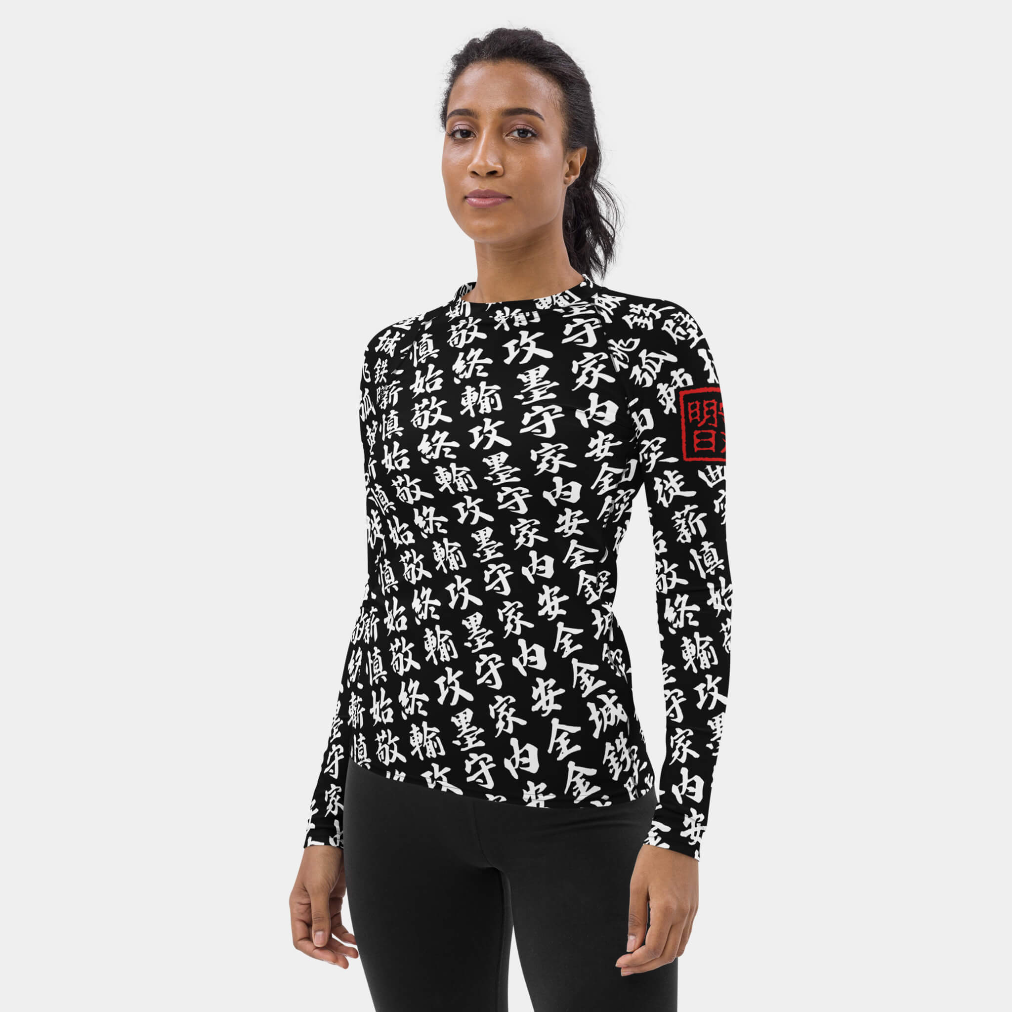 Woman wearing the SPARS TOO MUCH KANJI long-sleeve BJJ rash guard in Iron Black and White, with white kanji and a red seal on the left sleeve